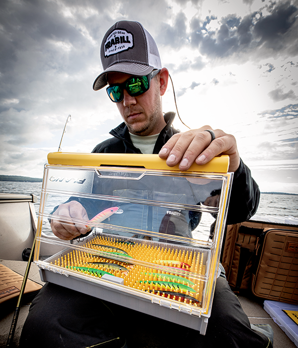 A man is organizing his Plano Stowaway while on a fishing boat on an overcast day. 